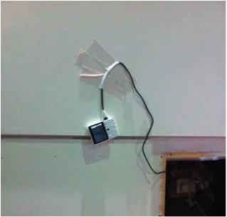 A photo of a smart phone duct taped to a wall.